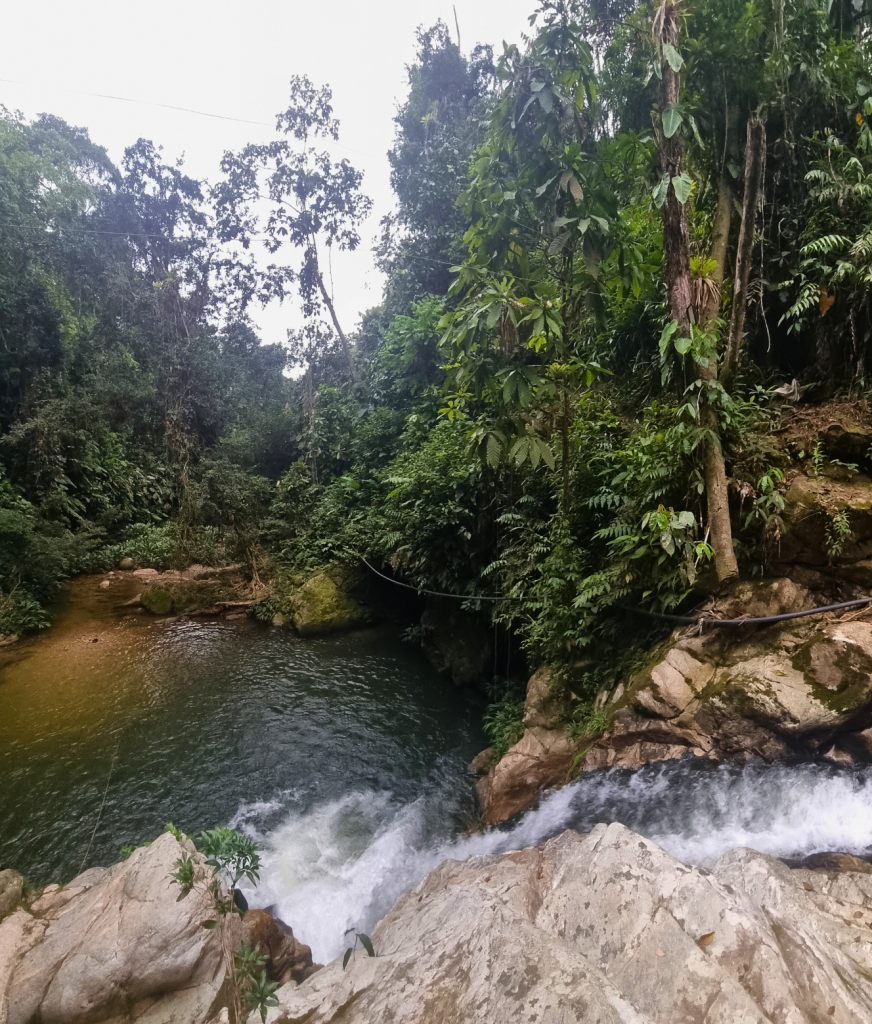 Clear jungle river with smooth rocks and green surroundings, a refreshing swimming spot along the Lost City Trek.